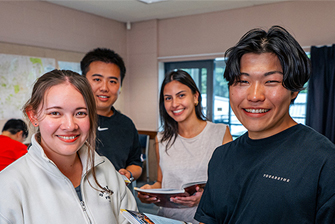 Two females and two males students standing in the classrom.